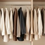 Dressing sobre présentant des vêtements en lin, laine et coton suspendus, dans une palette de tons naturels et neutres, avec une esthétique éditoriale réaliste.